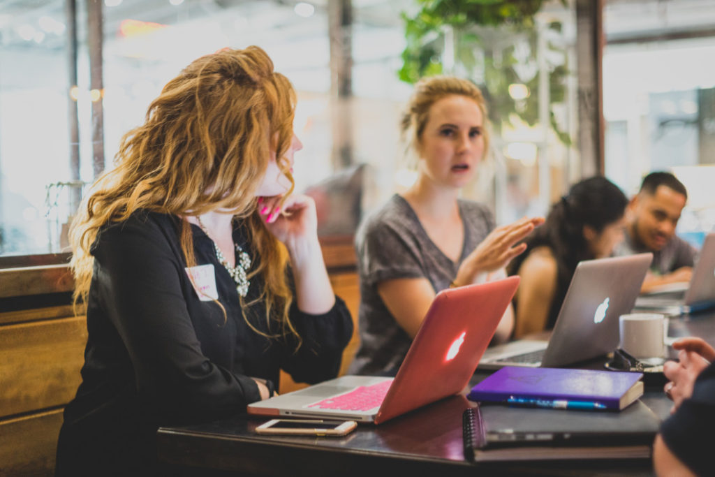 Two Women Talking and Working at Laptops